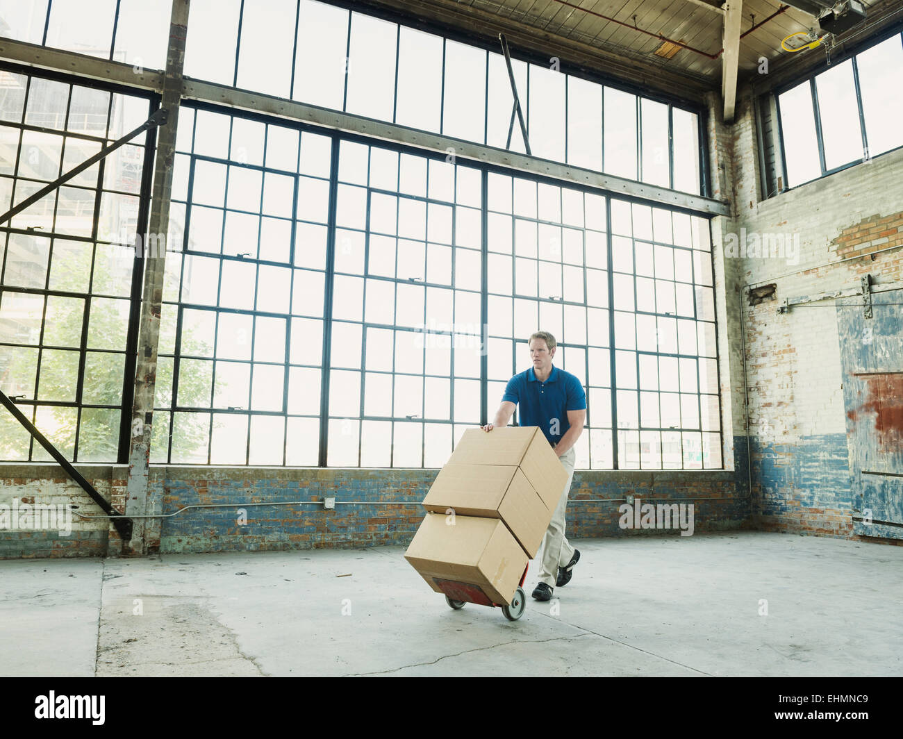Caucasian businessman pushing boîtes de carton sur camion de main dans l'entrepôt Banque D'Images