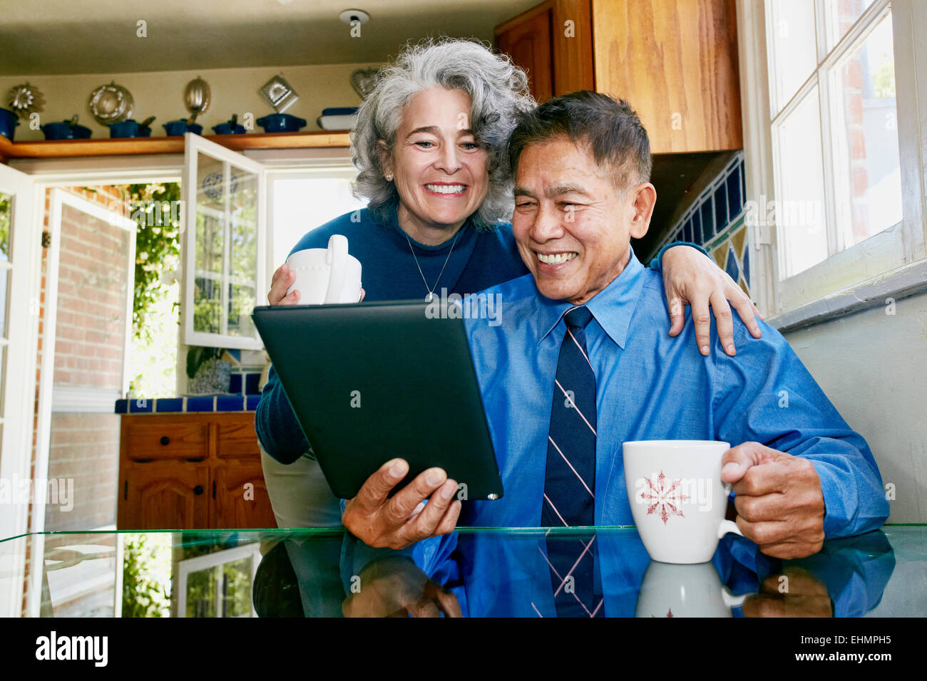 Couple using digital tablet in kitchen Banque D'Images