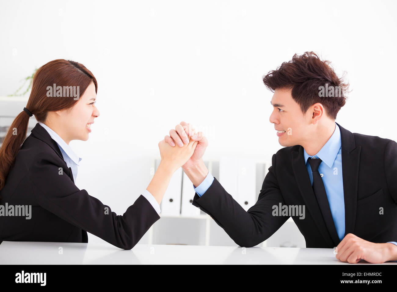Business man and woman Arm wrestling on desk in office Banque D'Images
