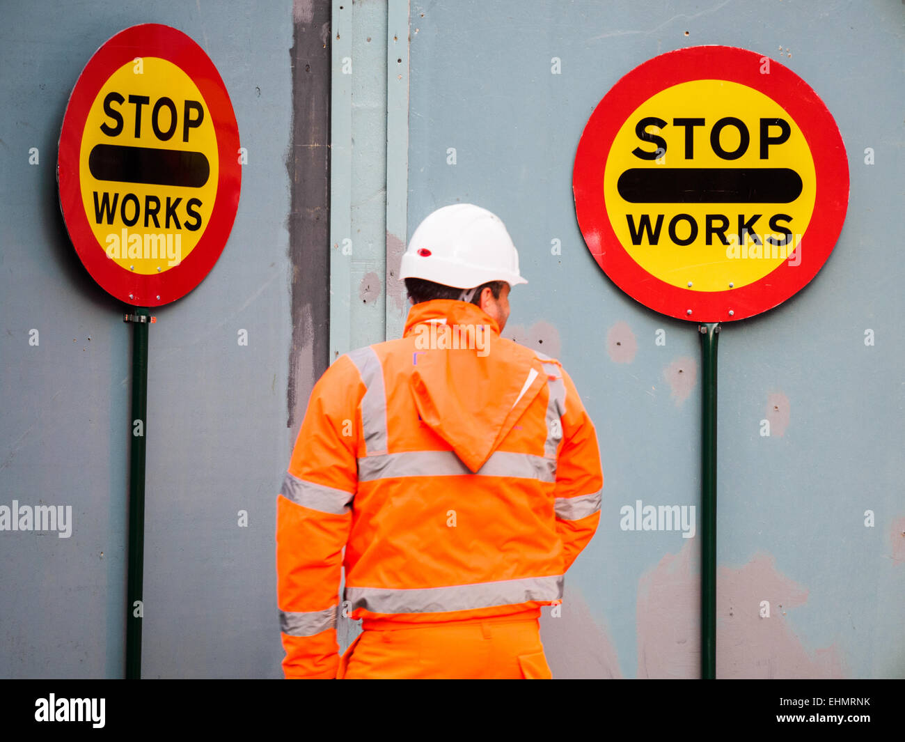 Un constructeur promenades par certains des signes de contrôle de la circulation à Londres UK Banque D'Images