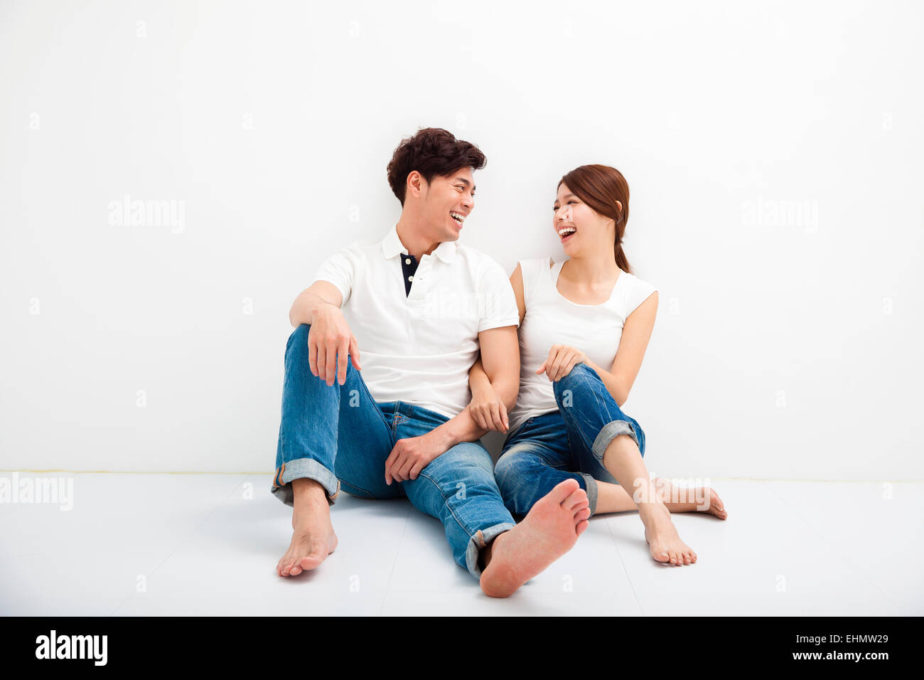 Happy Young Couple Sitting on Floor Banque D'Images