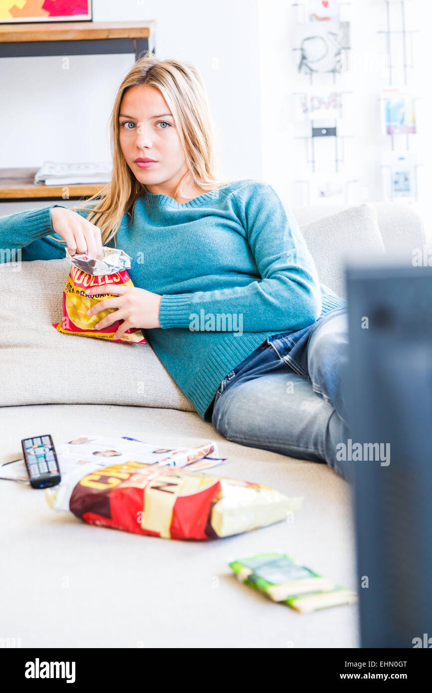 Femme de grignoter tout en regardant la télévision. Banque D'Images