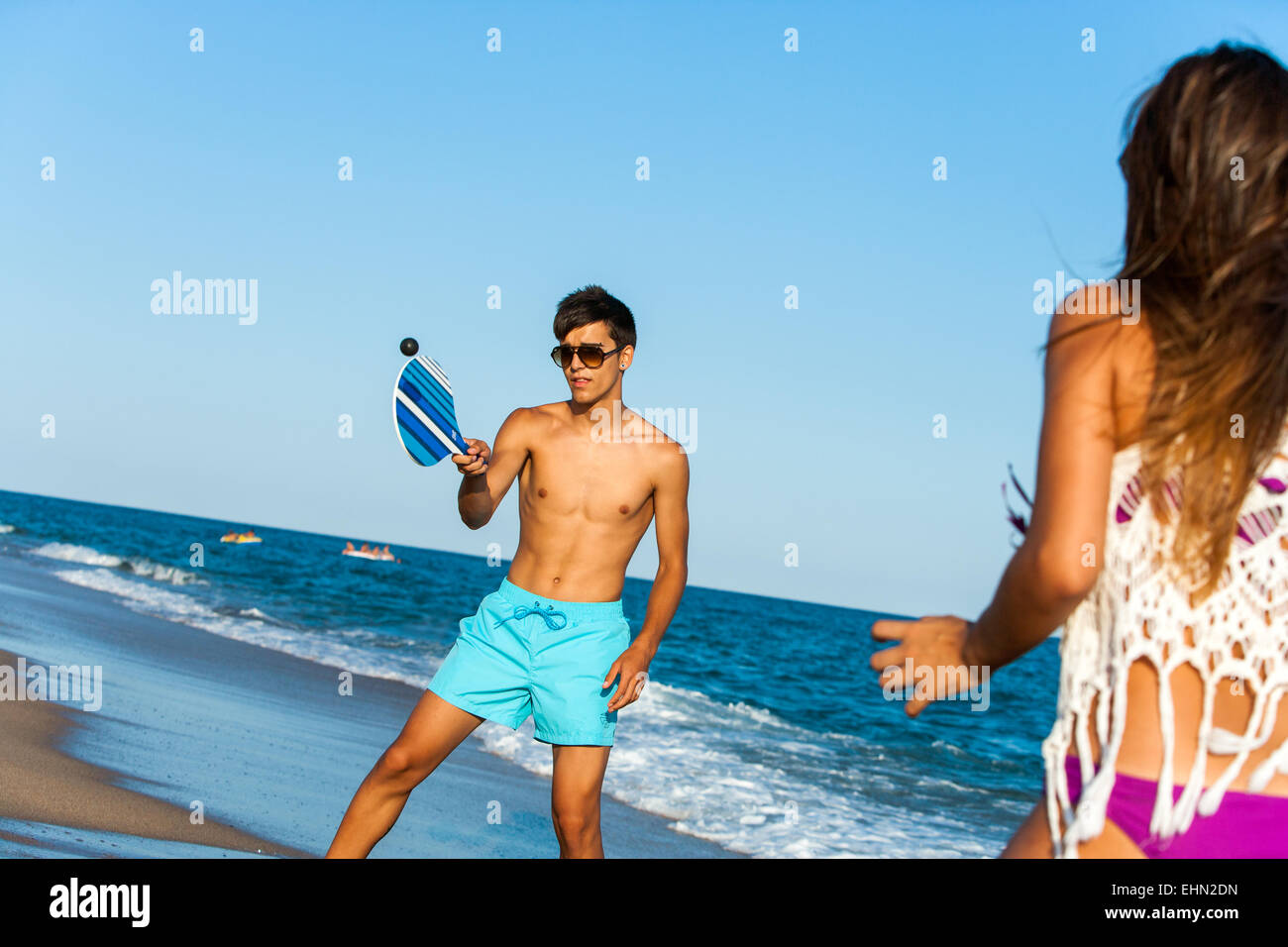 Jeune couple jouant balle smash tennis de plage à l'extérieur. Banque D'Images