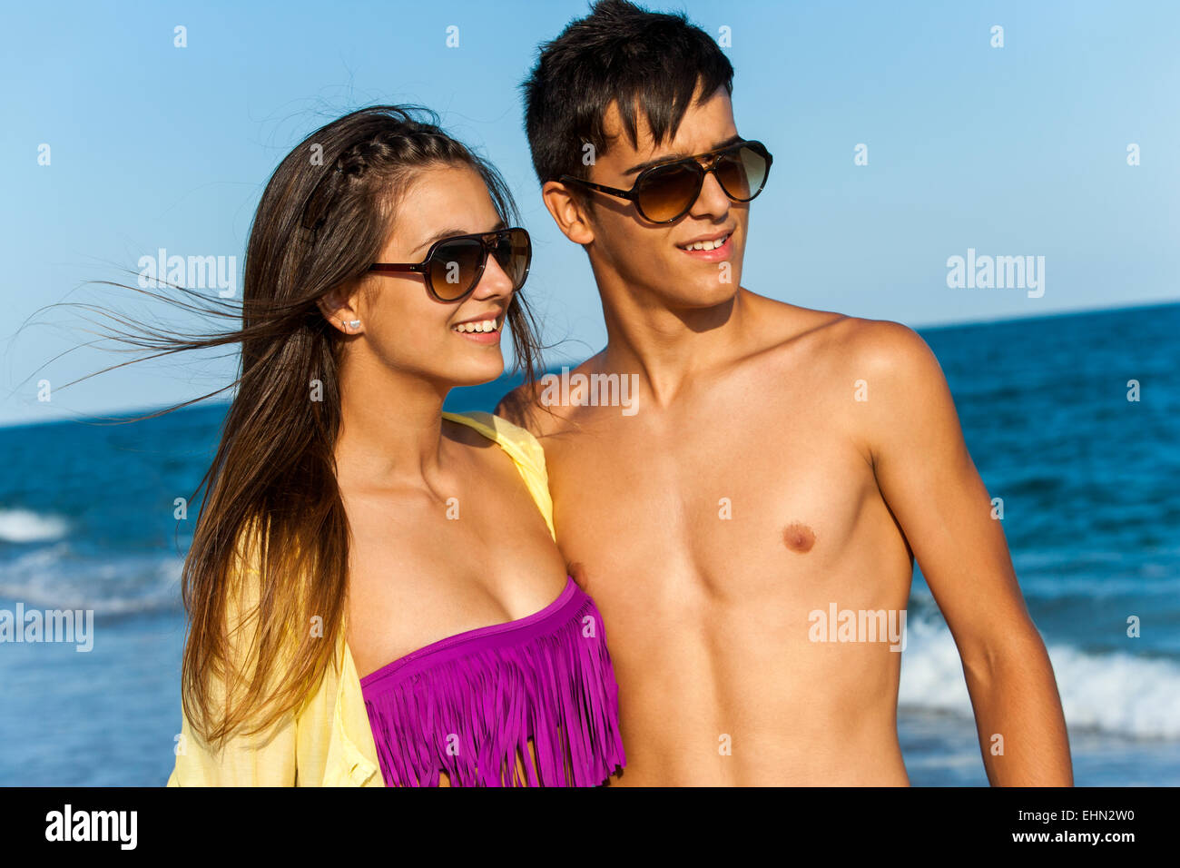 Portrait of cute teen couple standing on beach avec des lunettes. Banque D'Images