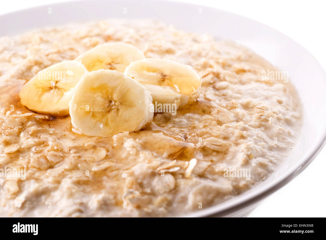 Un bol de porridge réchauffement avec tranches de banane et de miel/sirop. Banque D'Images