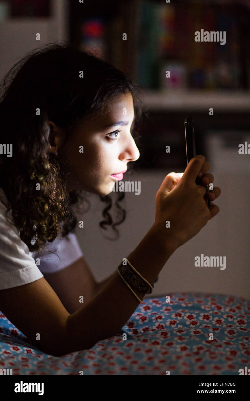 Adolescente en utilisant un smartphone dans la nuit. Banque D'Images