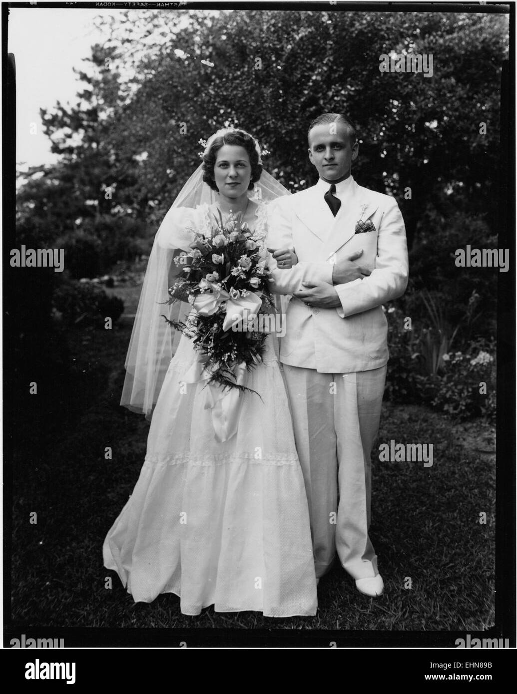 Ce portrait de mariage capture le couple dans une pose traditionnelle, soulignant l'importance du mariage. L'œuvre met en valeur la tenue vestimentaire et les coutumes culturelles associées aux mariages, en mettant l'accent sur la solennité et la joie de l'occasion. Banque D'Images