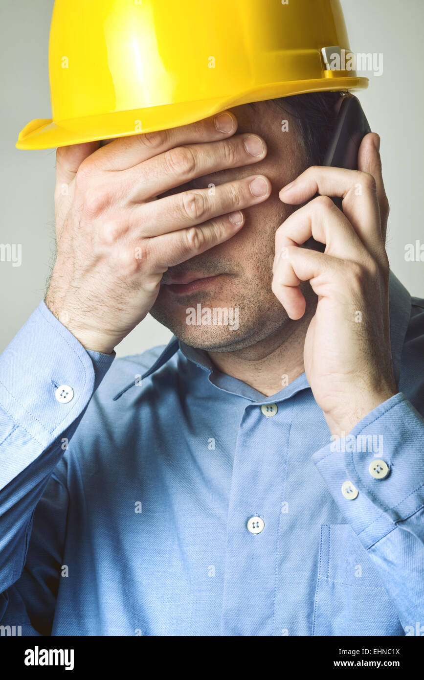 Ingénieur de construction vient d'entendre de mauvaises nouvelles à partir de ses employés au téléphone mobile. Banque D'Images