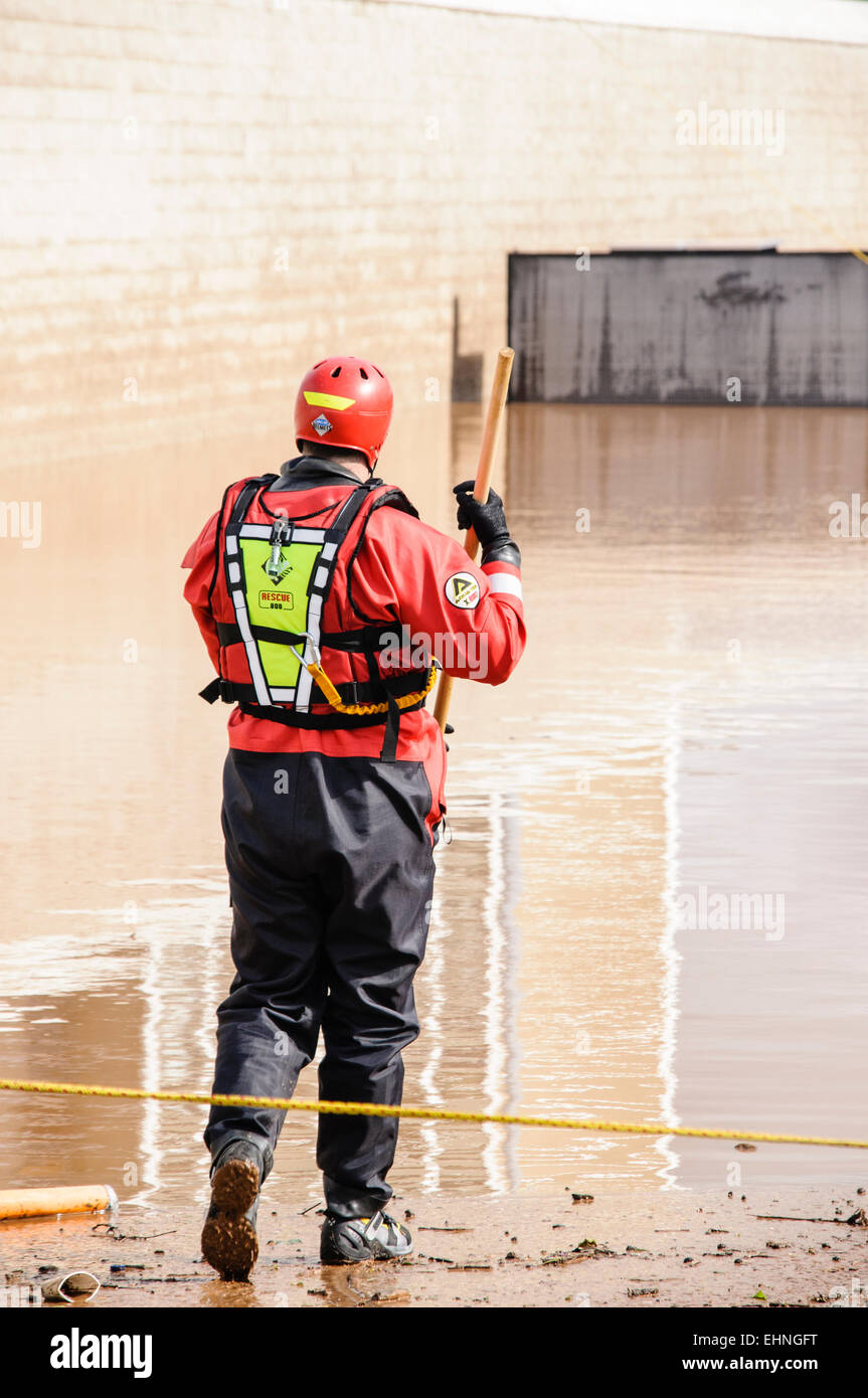 Le port d'un pompier combinaison étanche se tient au bord de l'eau de l'inondation Banque D'Images