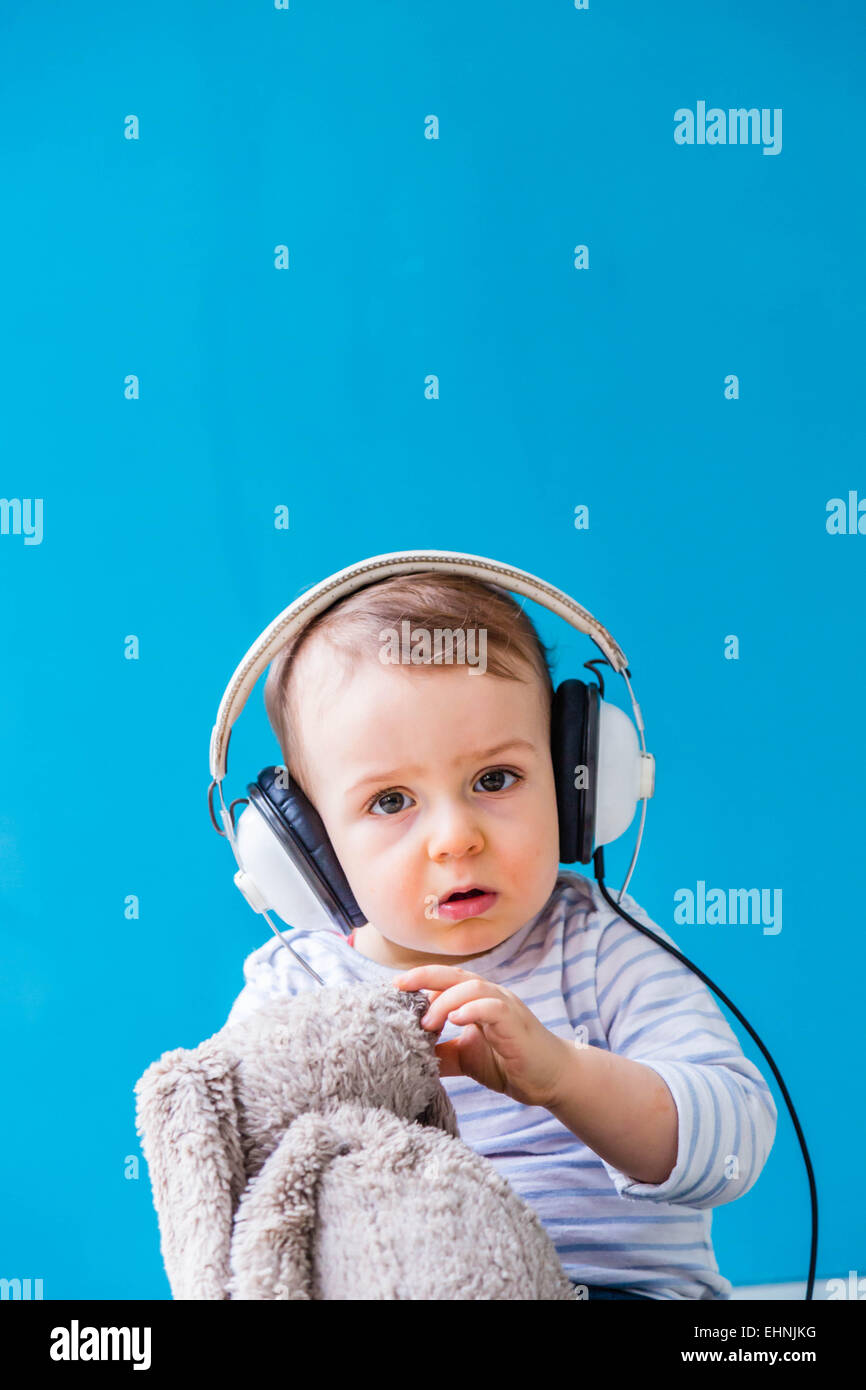 18 mois bébé garçon écoutant de la musique. Banque D'Images