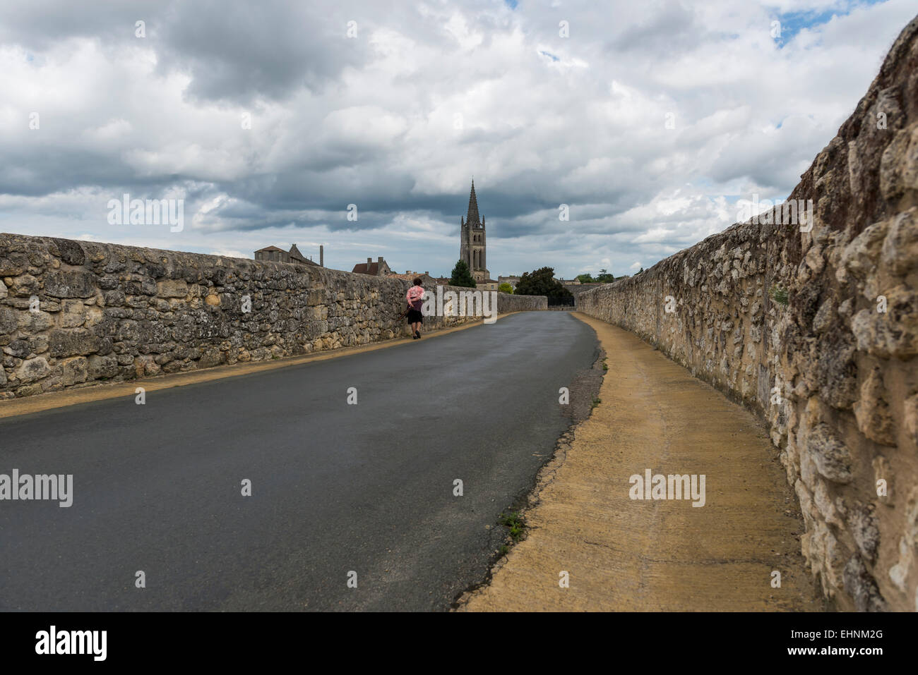 Road, Église et poussette sur une route noire à Saint-Emilion avec Ciel et nuages. Banque D'Images