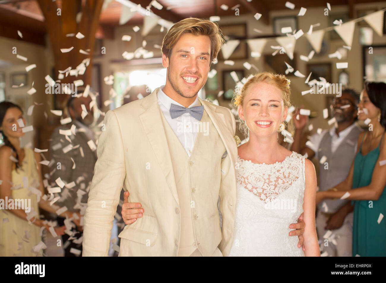 Portrait of smiling young couple standing in relevant des confettis pendant votre réception de mariage Banque D'Images