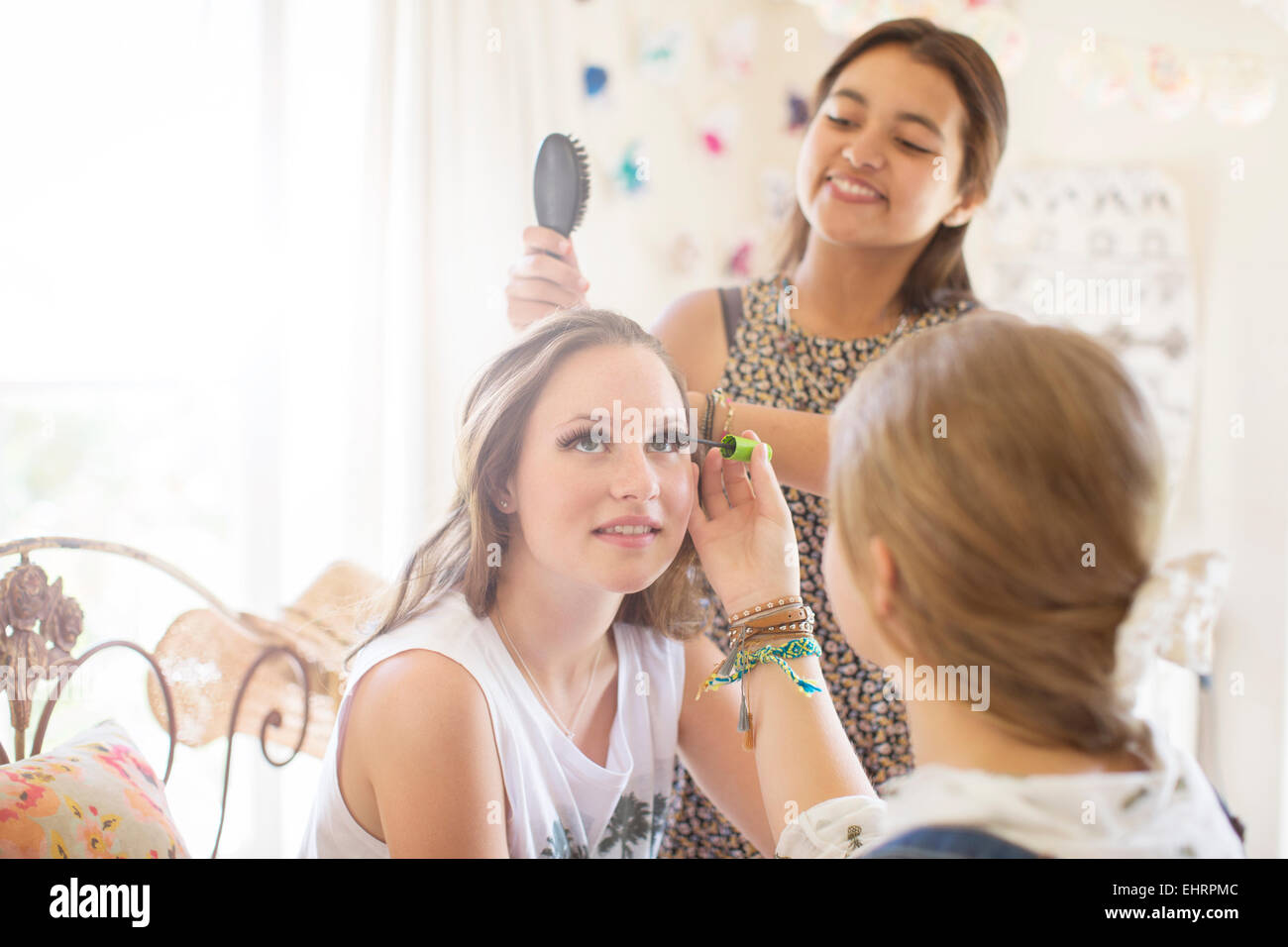 Trois adolescentes faisant le maquillage et cheveux brossage dans la chambre Banque D'Images