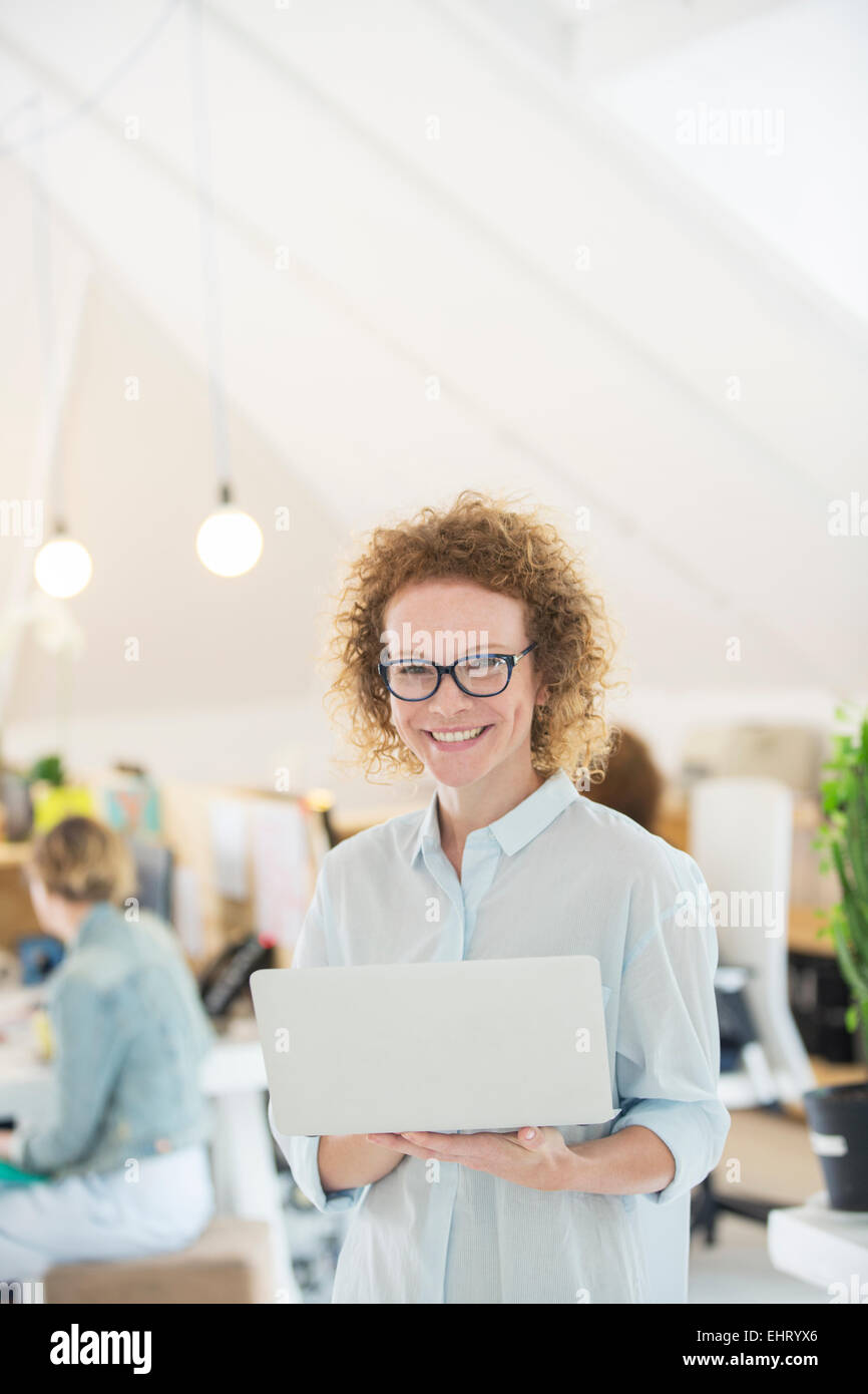 Portrait of woman holding laptop at office Banque D'Images