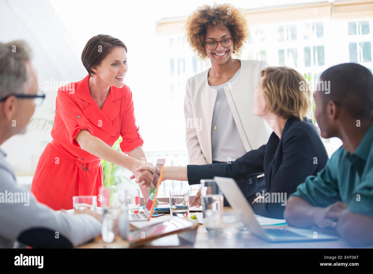 Les employés de bureau shaking hands at desk Banque D'Images