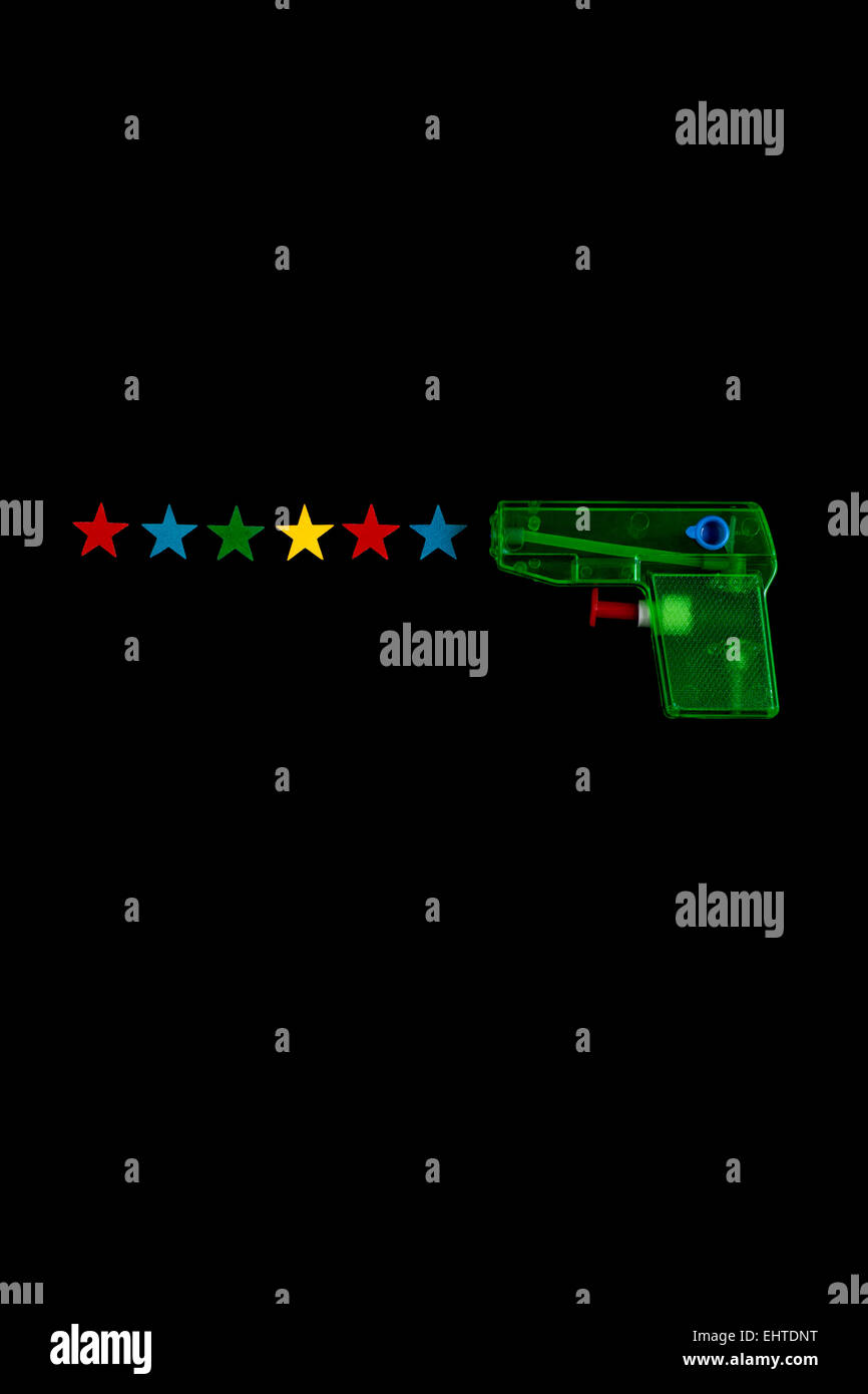 Pistolet à eau toy vert tiré six étoiles de différentes couleurs en plongée des sur fond noir Banque D'Images