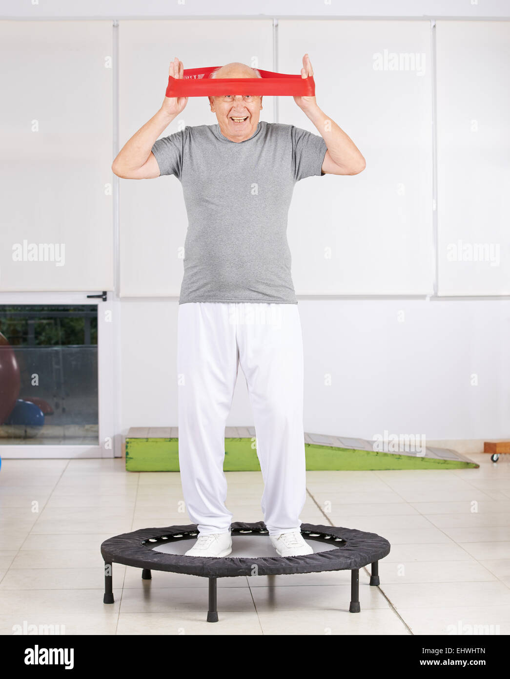 Vieil homme s'amusant avec l'exercice de la physiothérapie en bande sur un trampoline Banque D'Images