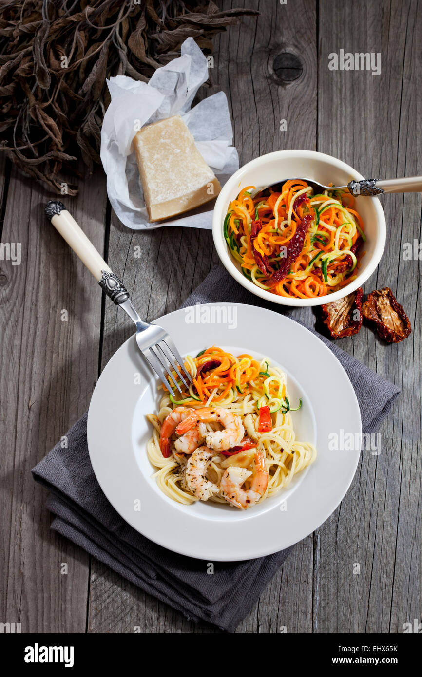 Spaghettis aux langoustines et légumes sur plaque, bol avec des spirales de tomates et courgettes, tomates séchées Banque D'Images