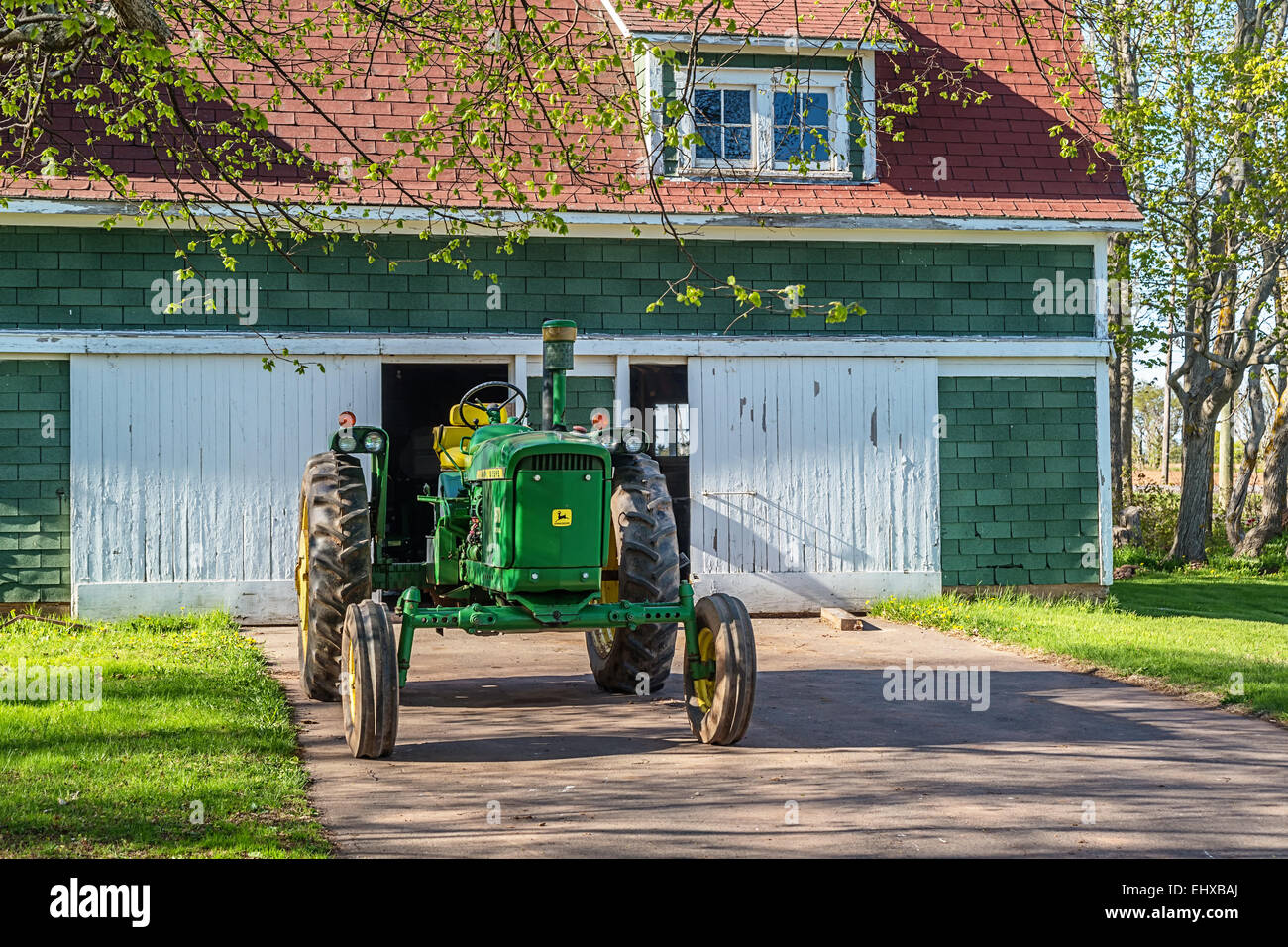 Vintage tracteur John Deere en face d'une ancienne grange. Banque D'Images