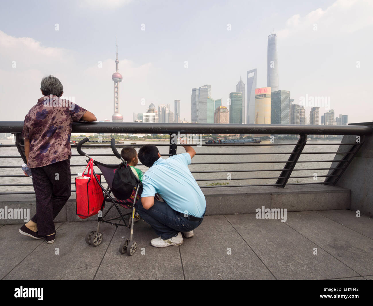 La grand-mère et le père de famille chinois avec un seul enfant sur une poussette de bébé profitant d'une vue sur le quartier de Pudong de Shanghai, Chine Banque D'Images