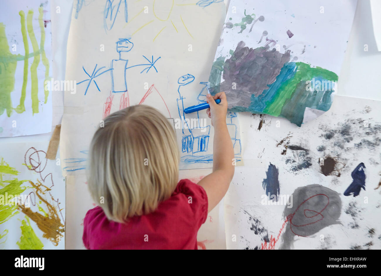 Petite fille peinture sur mur de chambre d'enfants, vue arrière Banque D'Images