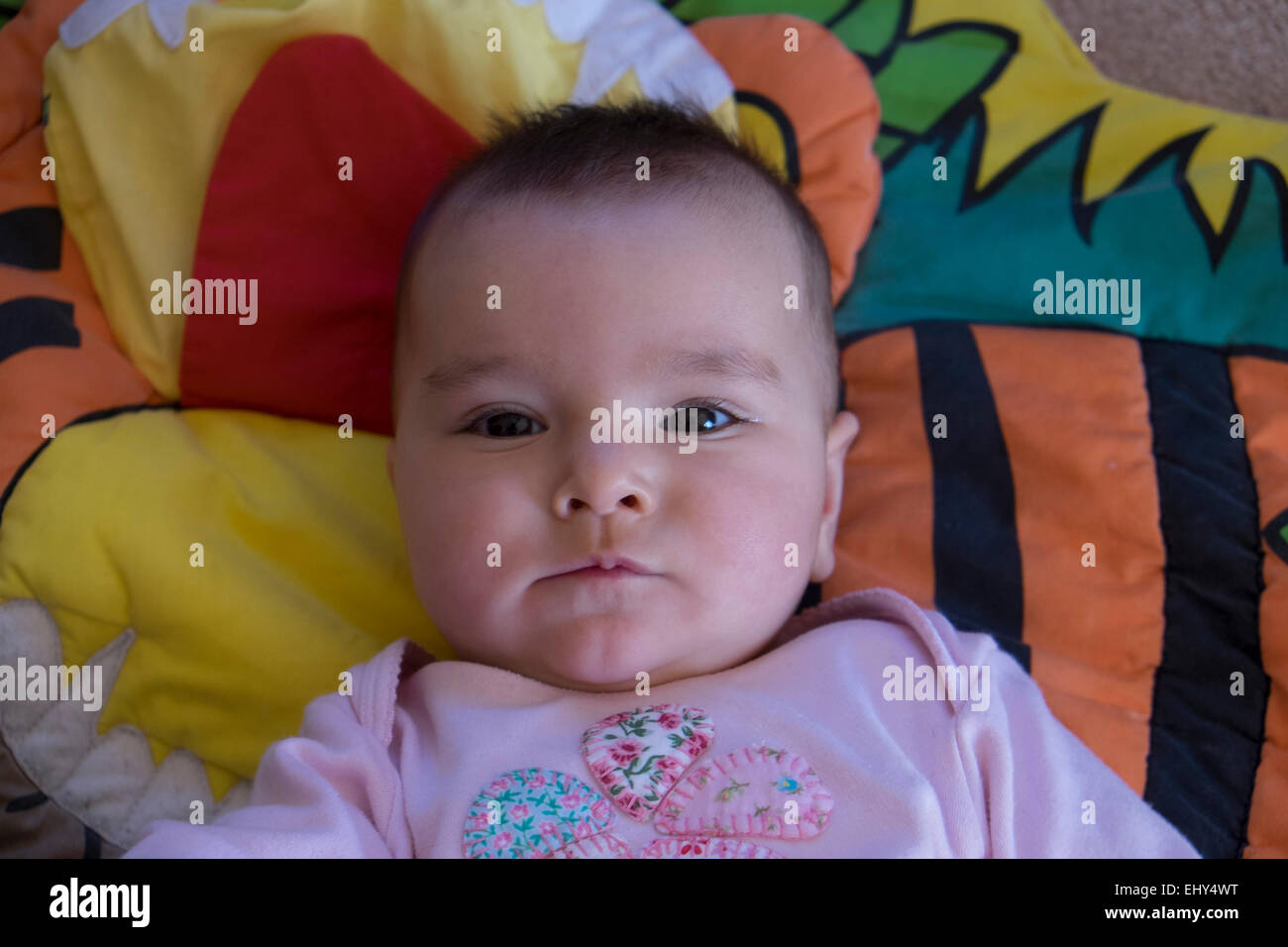 Bébé fille 8 mois, couché sur le plancher, smiling Banque D'Images