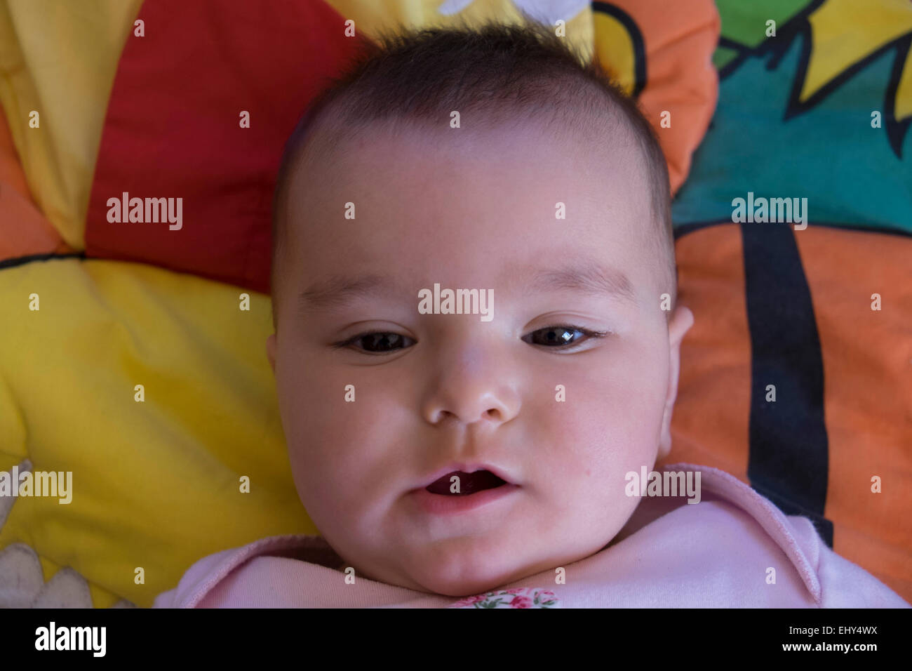 Bébé fille 8 mois, couché sur le plancher, smiling Banque D'Images