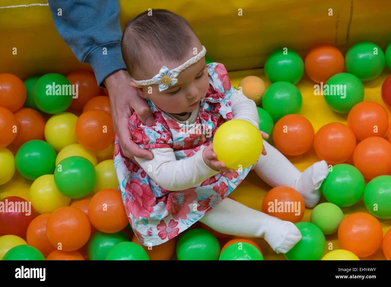 8 mois bébé fille, jouer avec des billes en plastique Banque D'Images