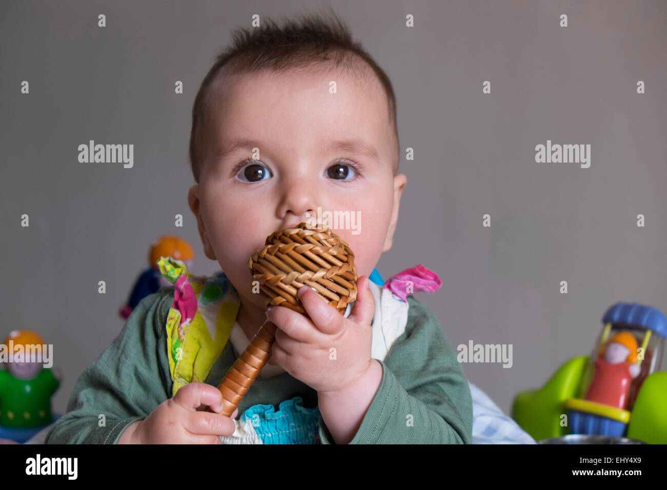 8 mois bébé fille, entourée de jouets dans baby bouncer, pleurer Banque D'Images