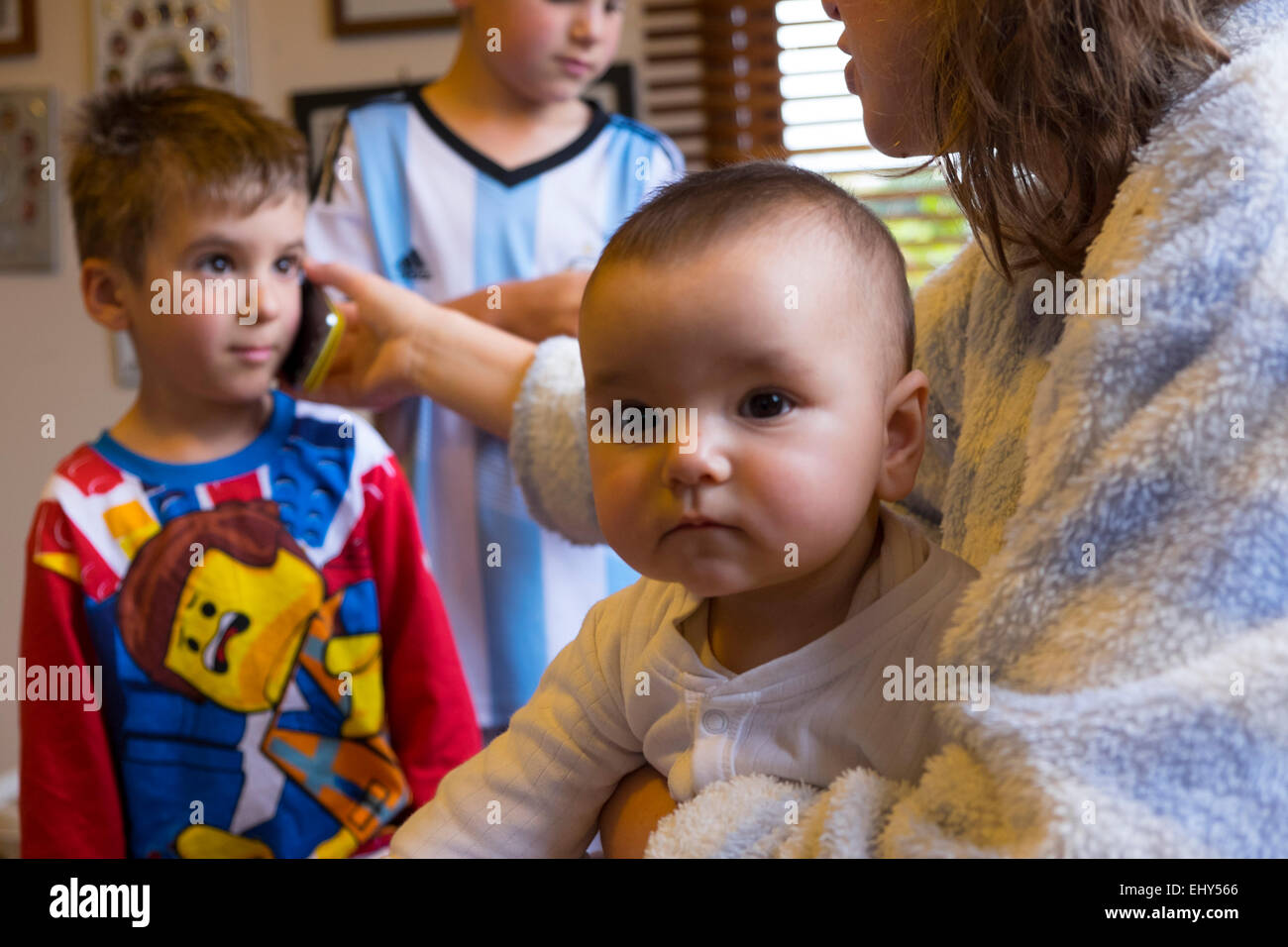 Enfant parlant au téléphone mobile avec d'autres membres de la famille Banque D'Images