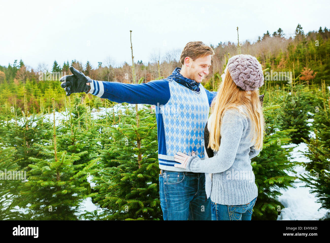 Happy young couple standing in front of Christmas Tree plantation Banque D'Images