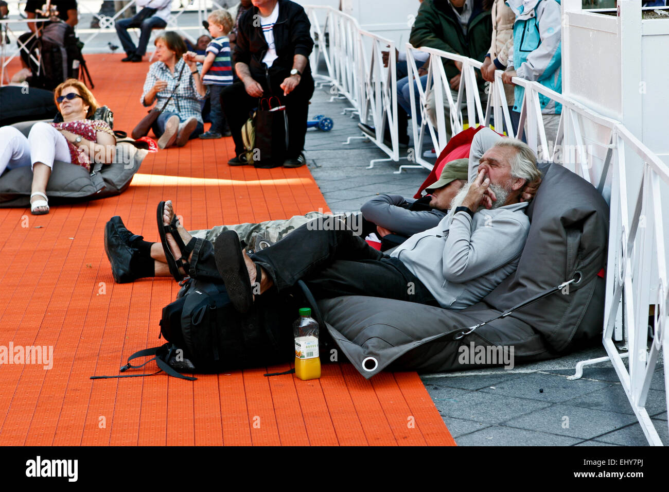 Homme âgé fatigué avec des cheveux blancs et une barbe, allongé sur le trottoir, relaxant et prenant son doigt vers le haut de son nez. Mauvais comportement. Paris, France, UE. Banque D'Images