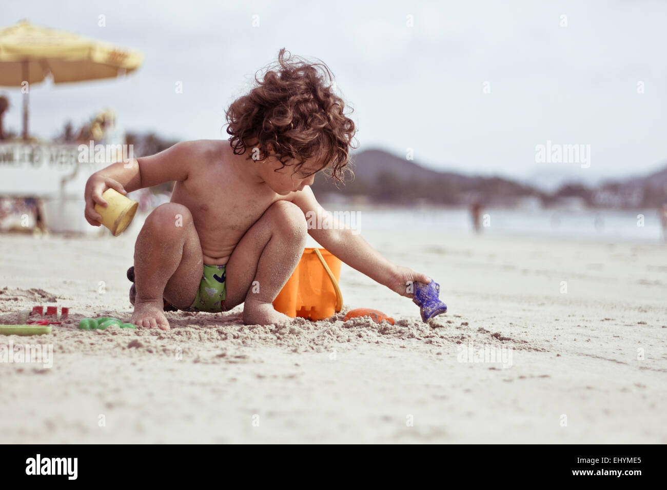 Garçon jouant dans le sable sur la plage, Brésil Banque D'Images