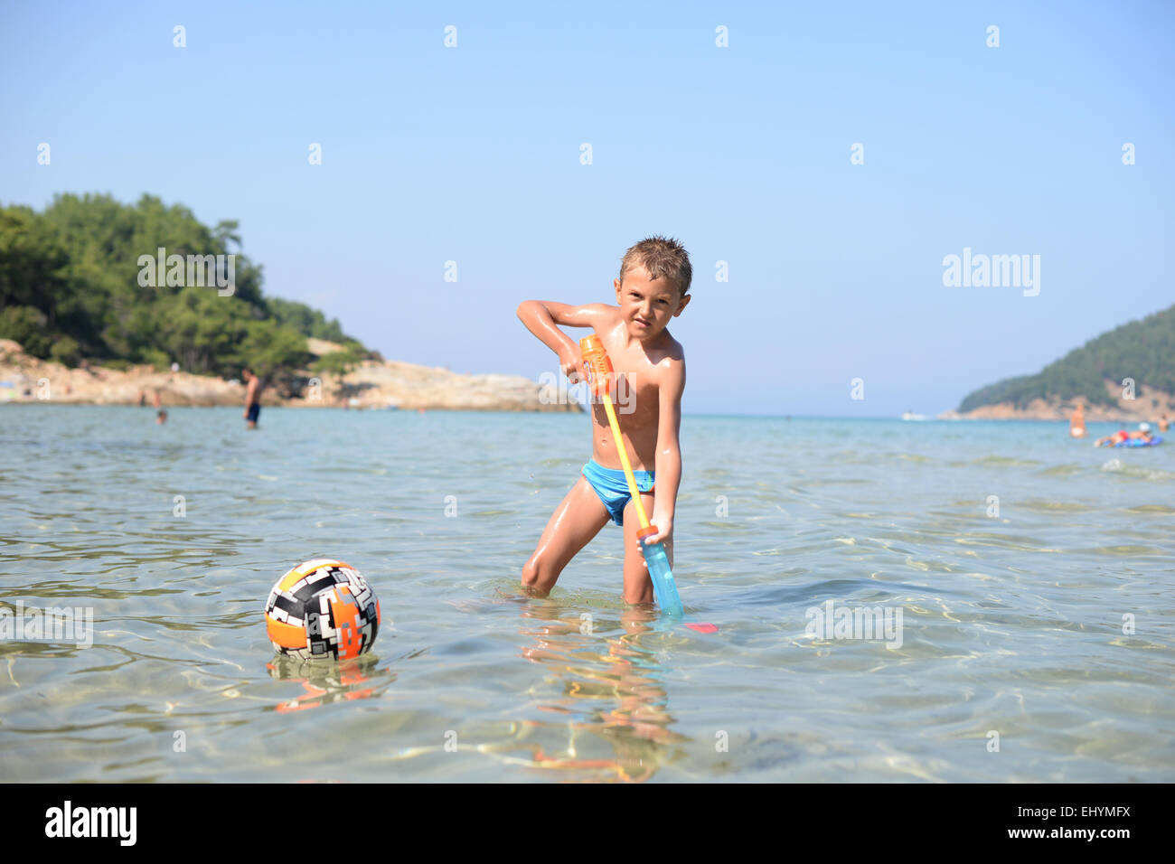 Garçon jouant dans la mer avec un canon à eau, Thassos, Grèce Banque D'Images