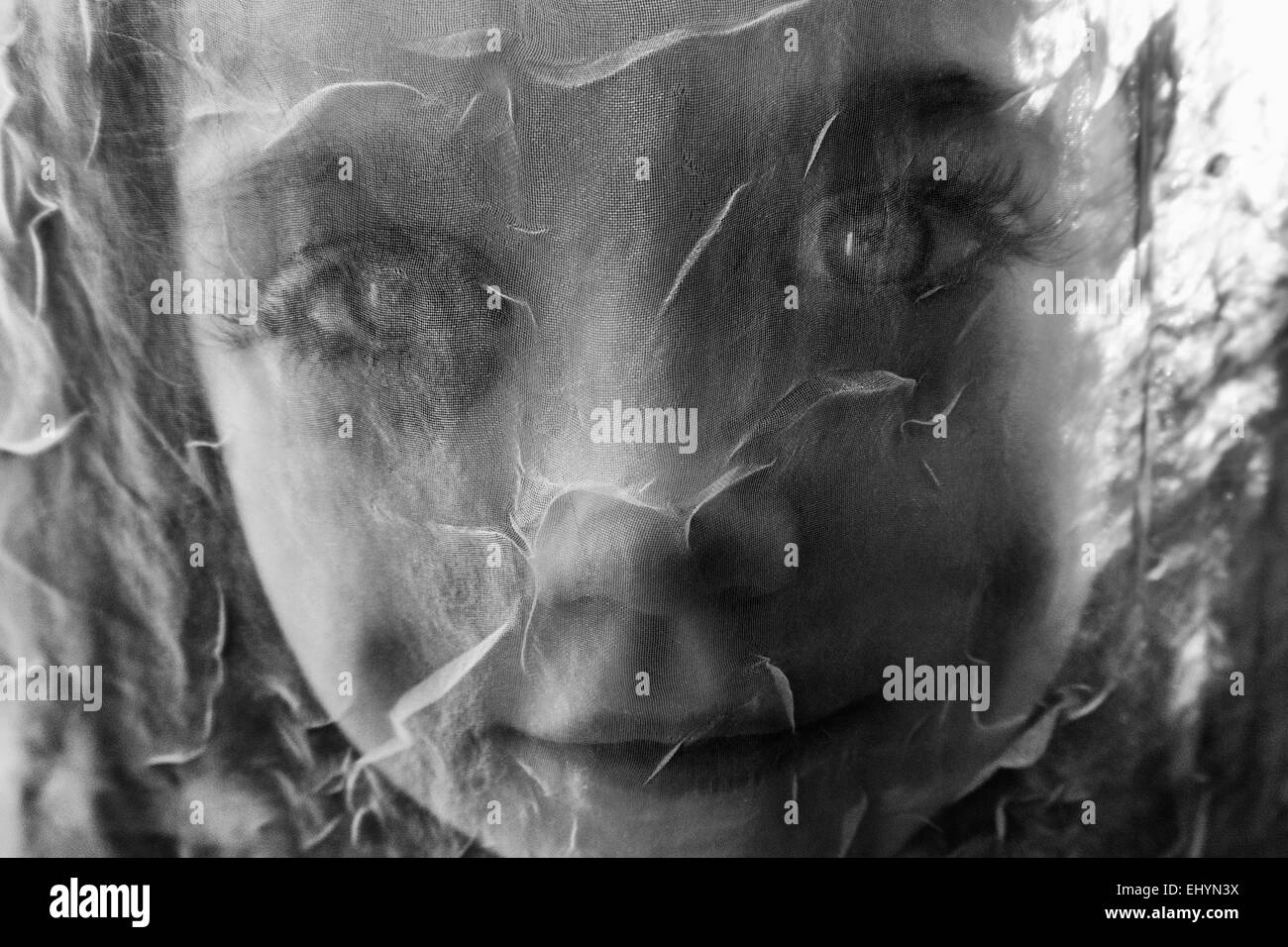 Portrait d'une fille regardant à travers un rideau de filet Banque D'Images