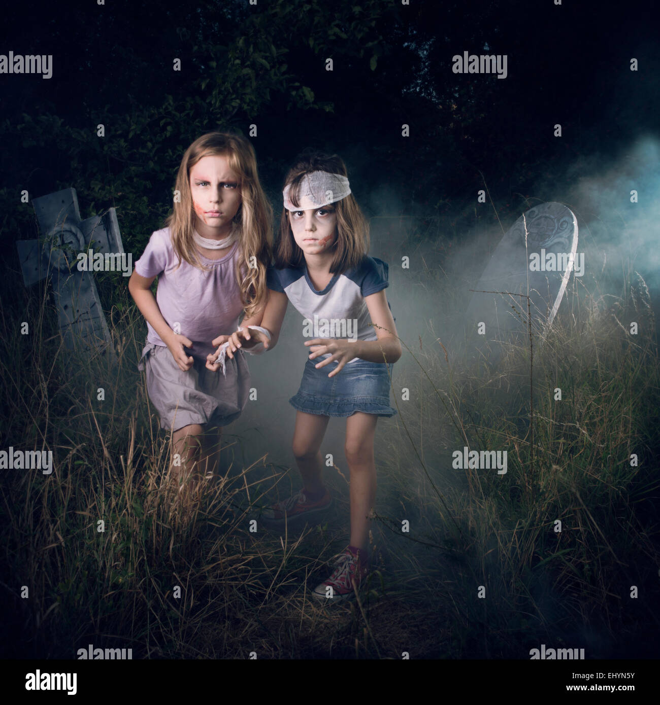 Deux jeunes filles se faisant passer pour des zombies dans un cimetière à l'Halloween Banque D'Images