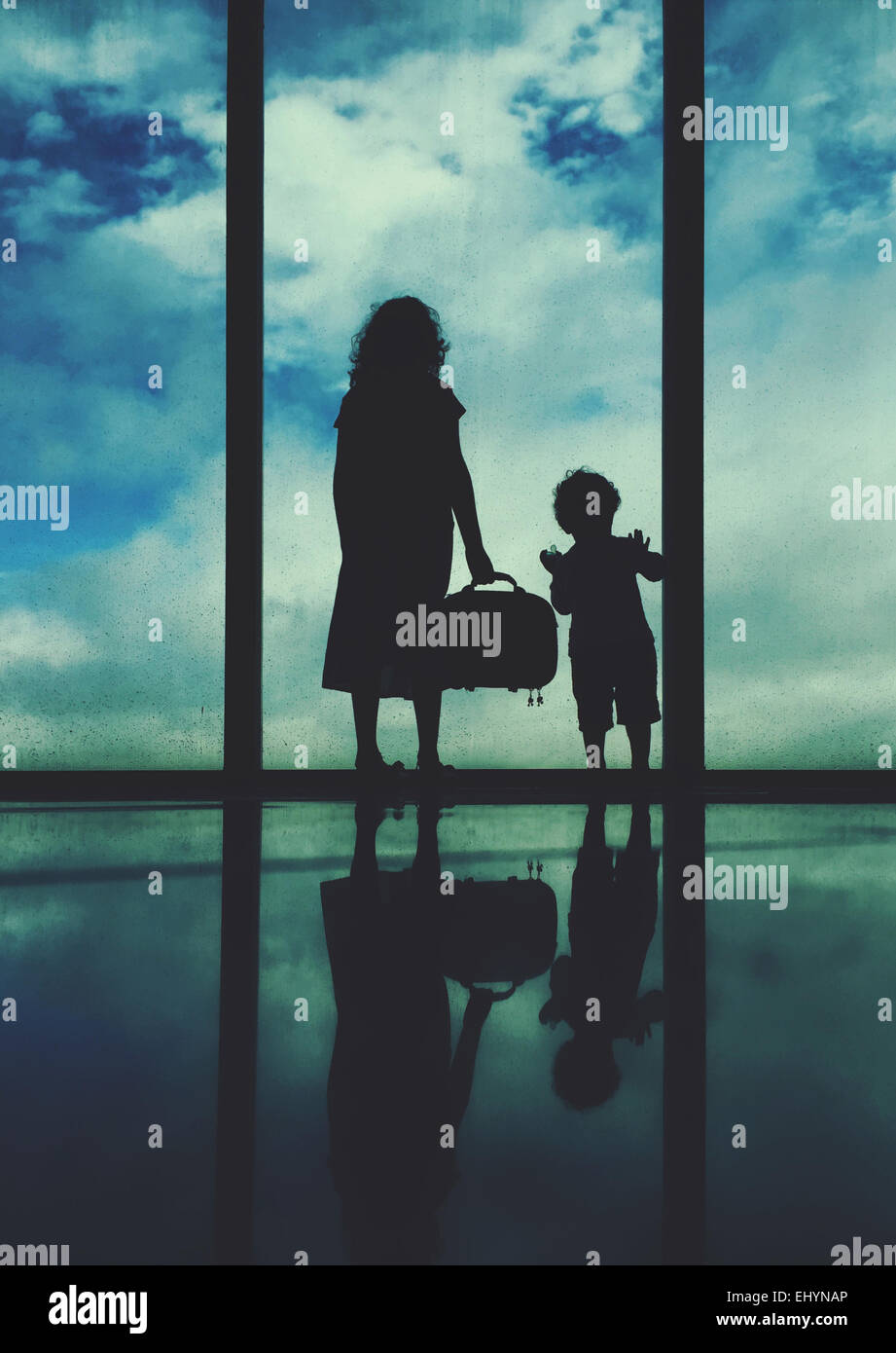 Silhouette d'une femme et le garçon debout à une fenêtre de l'aéroport Banque D'Images