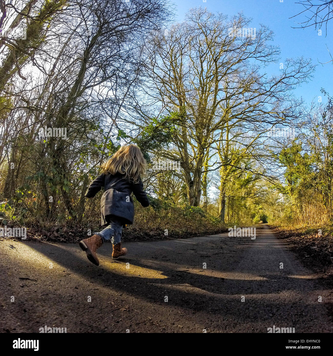 Vue arrière de fille courir en bas de la route Banque D'Images