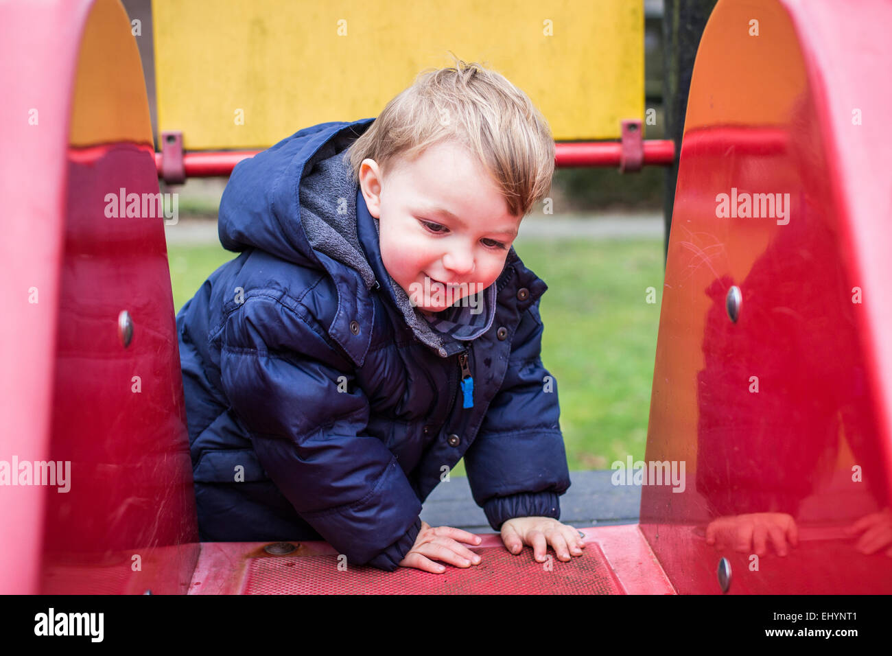 Bébé garçon escalade sur une diapositive Banque D'Images