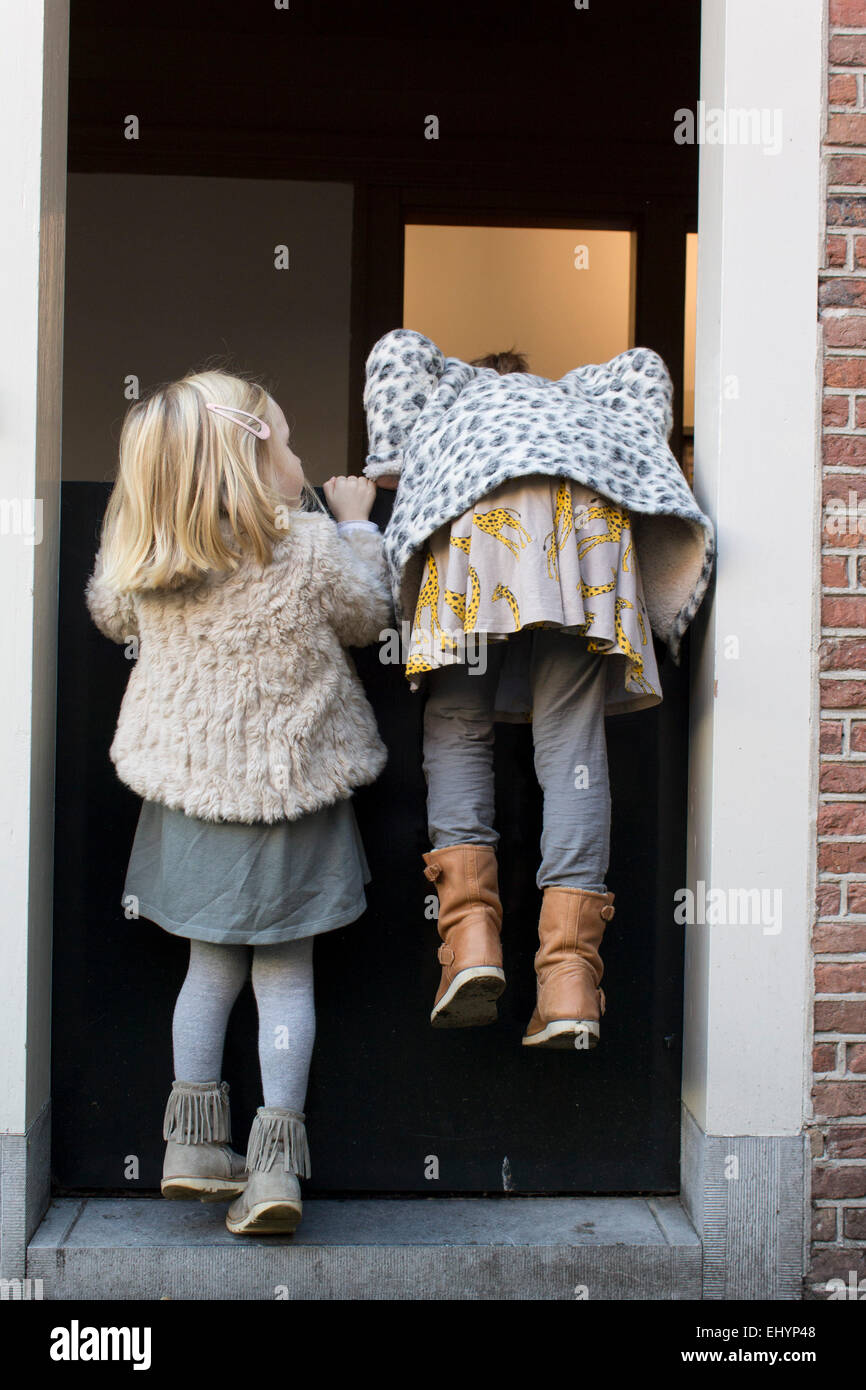 Deux filles essayant de grimper sur une porte hollandaise Banque D'Images