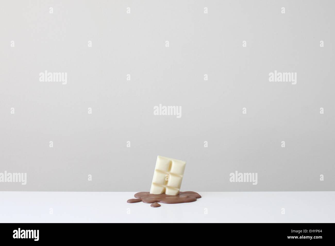 Bar conceptuel de chocolat blanc dans un pool de chocolat au lait fondu Banque D'Images