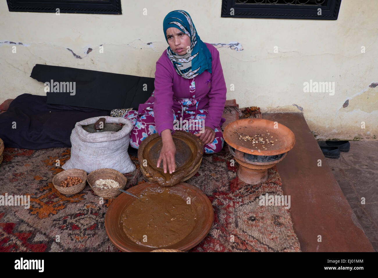 Femme d'argan (Argania spinosa de broyage d'amandes) pour le processus de fabrication traditionnelle de l'huile d'argan, vallée de l'Ourika, Atlas Pe Banque D'Images