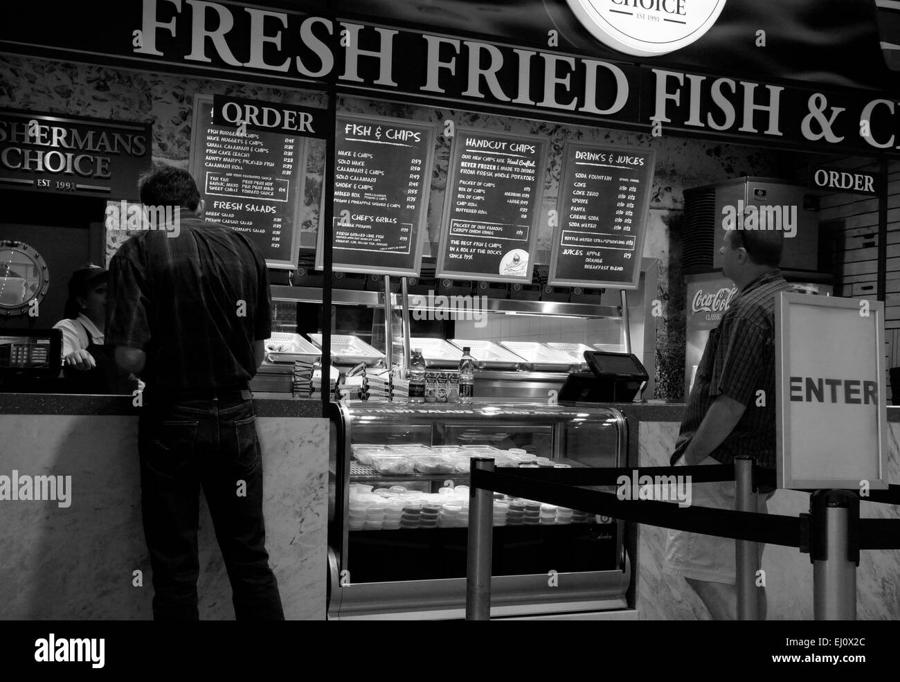 Les hommes de commander du poisson et des frites dans un restaurant au V&A Waterfront à Cape Town. L'Afrique du Sud. C noir et blanc Banque D'Images