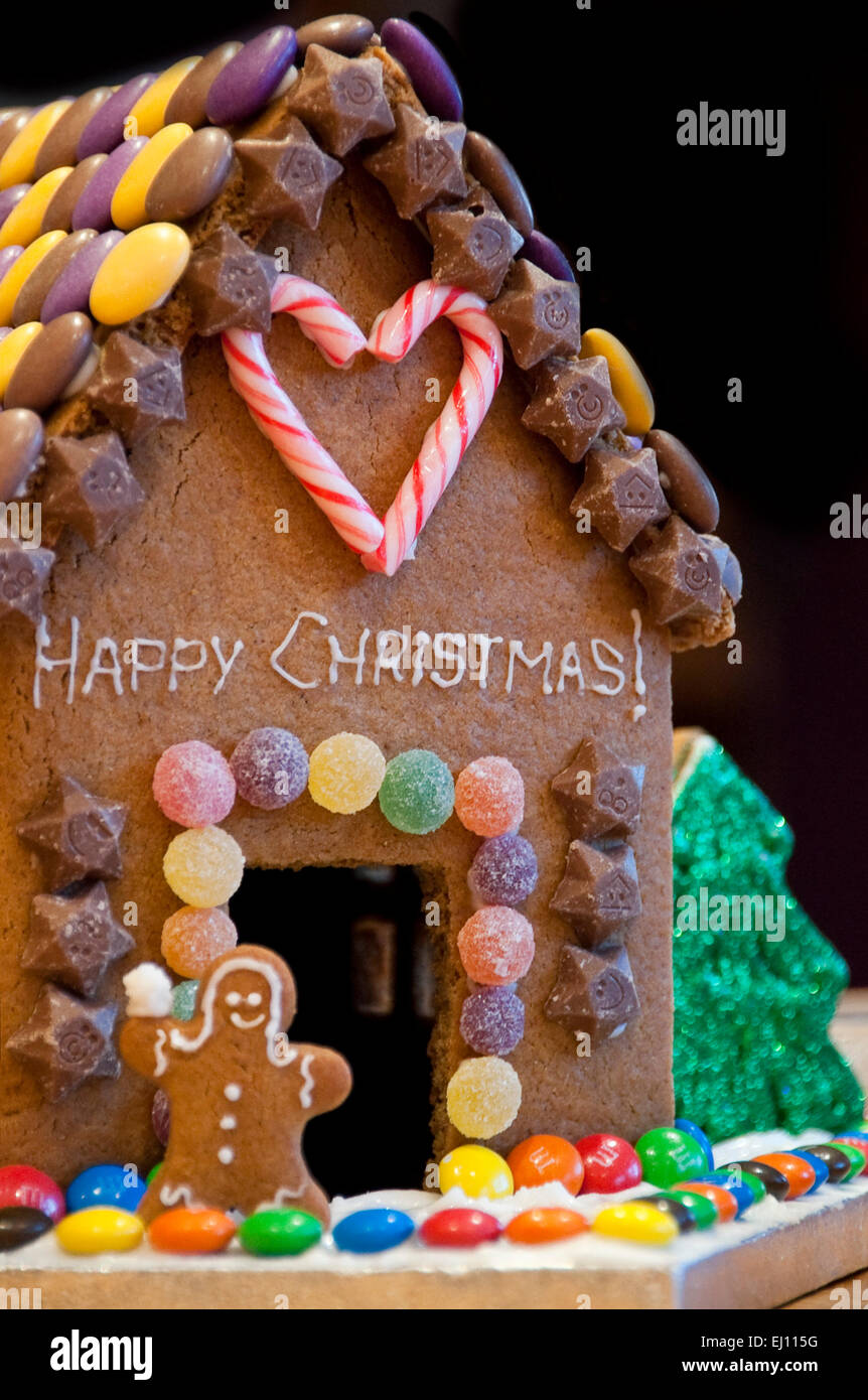 Close up vertical d'une maison en pain d'épices maison décorée pour Noël avec des arbres de Noël et de la neige. Banque D'Images