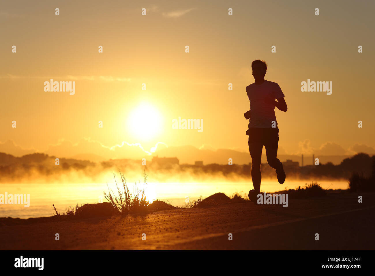 Silhouette d'un homme qui court au lever du soleil avec le soleil en arrière-plan Banque D'Images