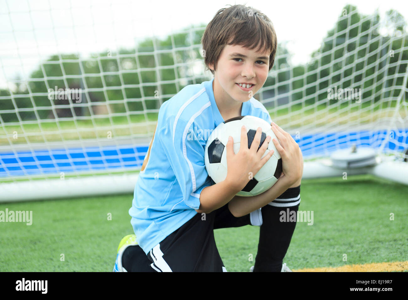 Jeune joueur de foot avec ballon sur le terrain Banque D'Images