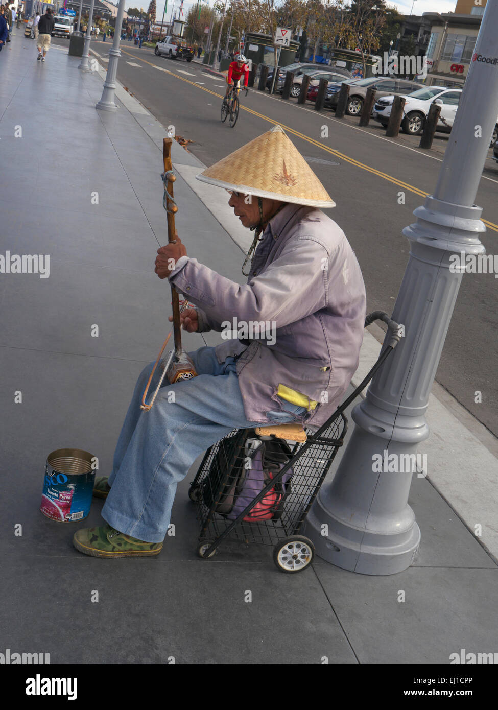 Busker mâle oriental wearing straw coolie hat et la lecture d'un Erhu, Le violon chinois deux chaînes sur trottoir pour les trucs au crépuscule Banque D'Images