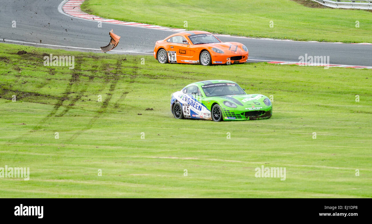 Deux voitures Ginetta Junior course dans l'herbe après une collision à Oulton Park circuit international Banque D'Images