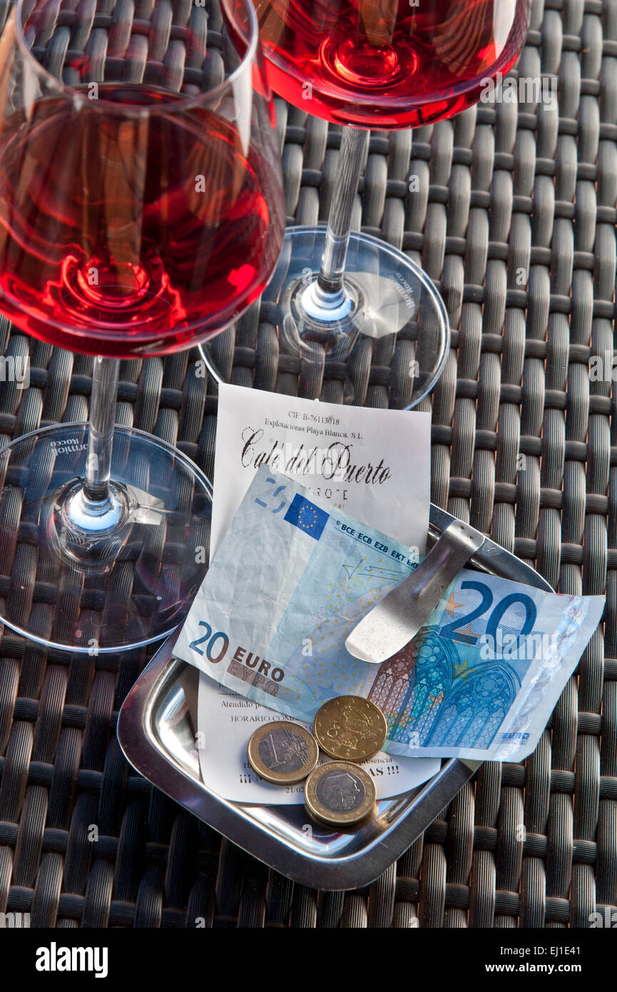 EUROS vérification de la facture du restaurant avec paiement en euros sur la table du restaurant espagnol avec deux verres de vin rose ensoleillé Espagne Banque D'Images