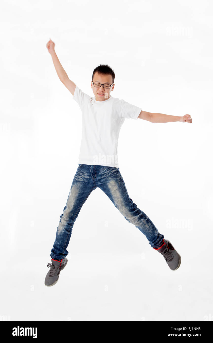 Teenage boy jumping in mid-air with arms outstretched Banque D'Images